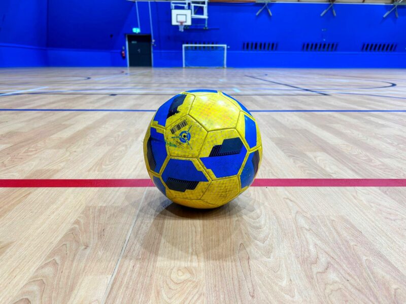 A single football motionless on the floor of Inspire's sports dome