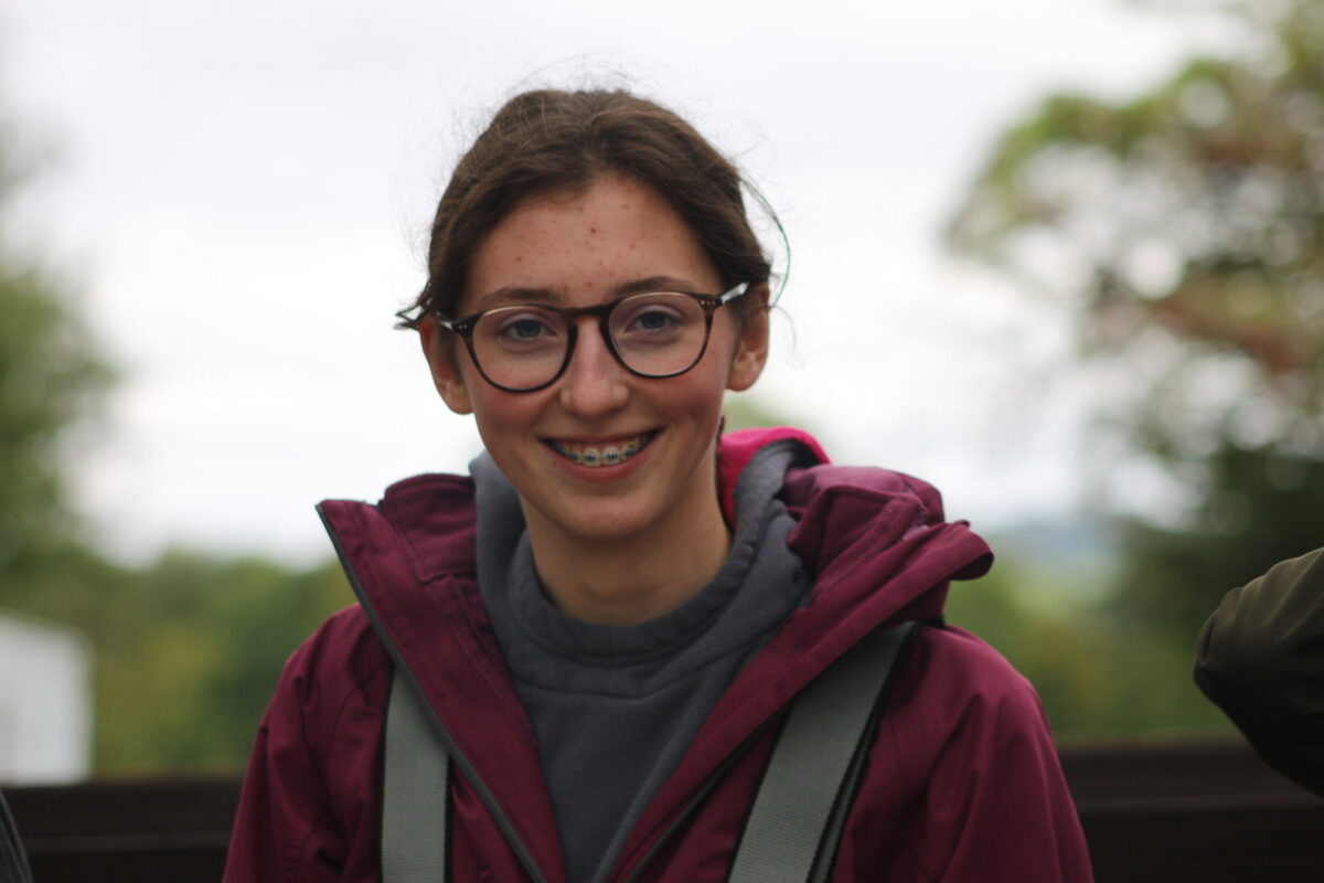 A young person from Inspire smiles at the camera while wearing a safety harness for a zipline.