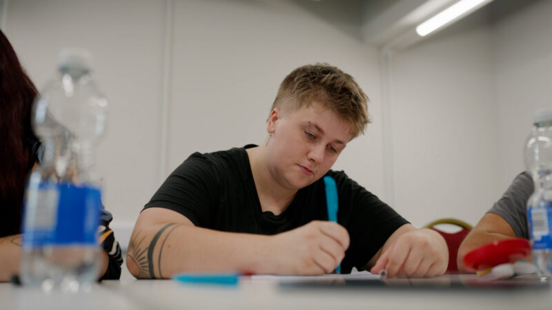 Jed, an Inspire student, sits at a desk doing coursework.