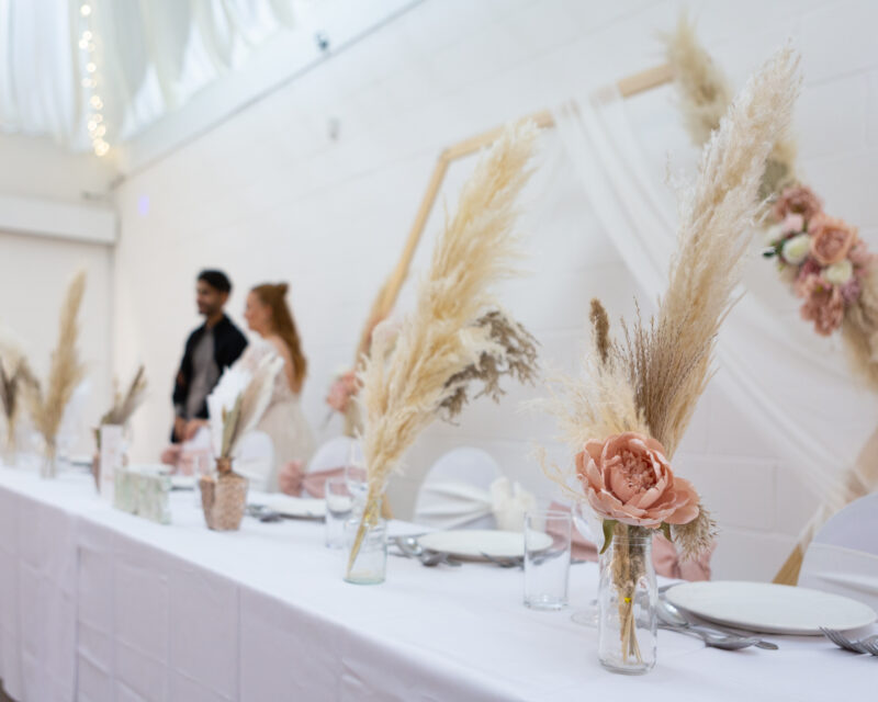 An image of a bride and groom in Inspire's events hall behind the top table, adorned with flowers.